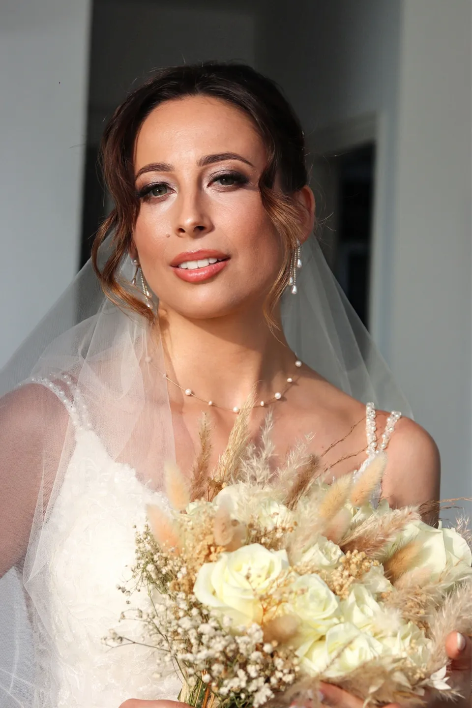 Bride with veil and dried flower bouquet, luminous bridal makeup