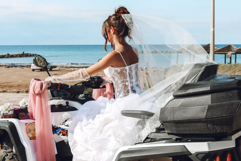 Bride in tulle on a quad bike by the sea